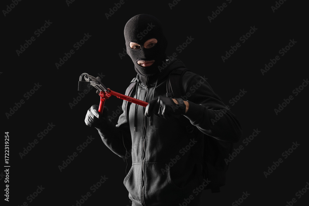 Naklejka premium Male thief breaking lock on black background