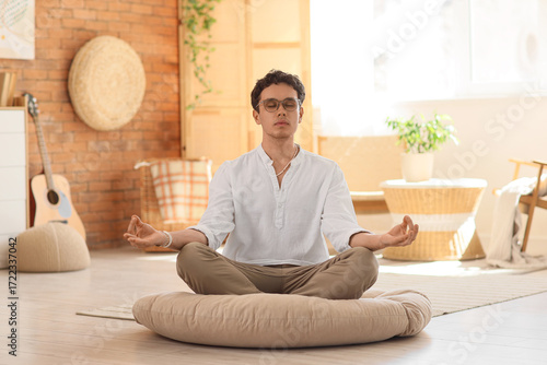 Young man meditating on pou...