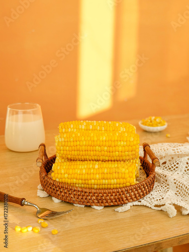 Obraz na plátně Fresh Corn Cobs in Rustic Wicker Basket on Kitchen Table with Warm Golden Light