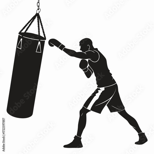Silhouette of a male boxer in action throwing a punch at a heavy training bag in a gym