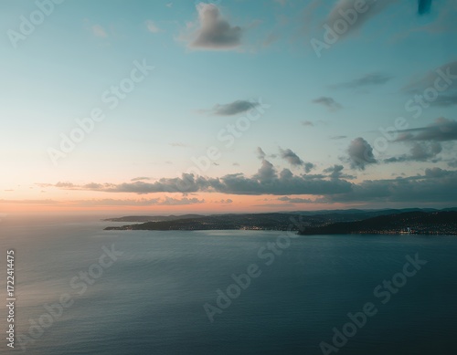 Serene twilight over the calm ocean, showcasing vibrant hues and distant hills.