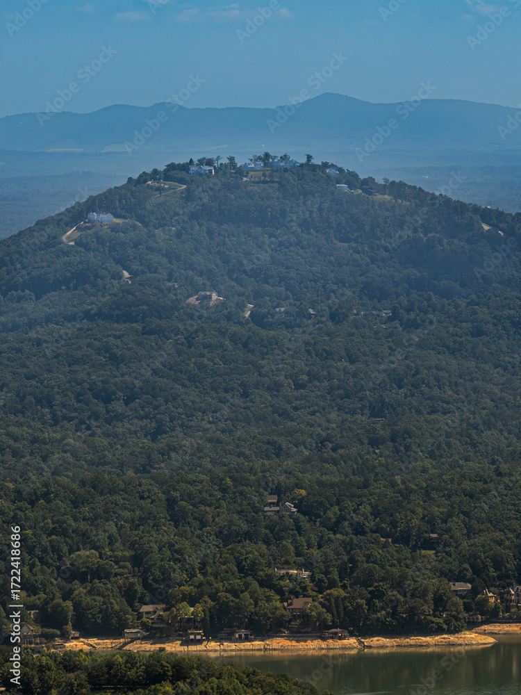 Fototapeta premium Scenic view of mountain ridges covered with dense forest and scattered houses on the slopes