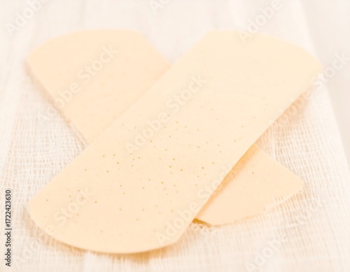 Two light beige adhesive bandages on a white cloth