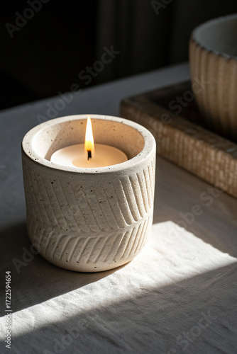 Lit candle in textured ceramic holder flame