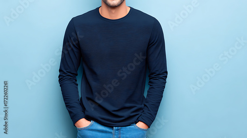 Man wearing a dark blue long sleeve t shirt and blue jeans with hands in pockets