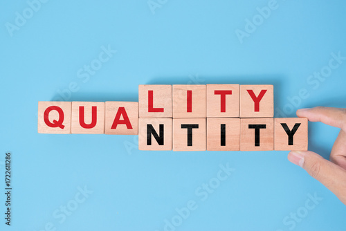 Quality over quantity concept. Hand changing word quantity to quality on wooden blocks.