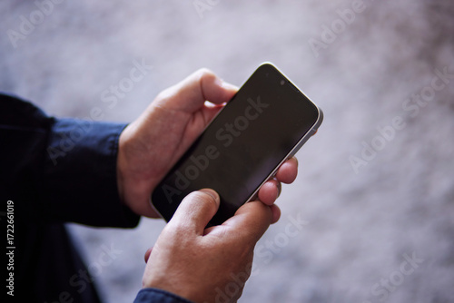 スマートフォンを操作する日本人シニア男性の手元