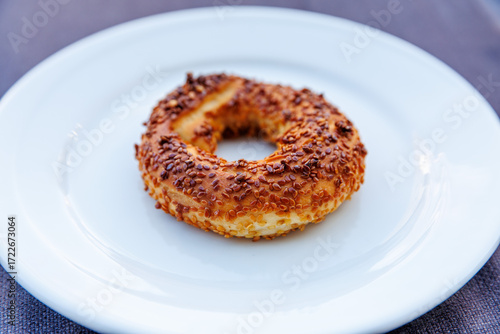 Delicious turkish sesame bagel on white plate. The golden-brown crust covered with sesame seeds, adding touch of texture and flavor to this beloved baked treat.