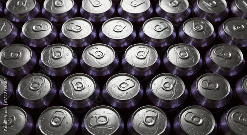 A high-angle view of metallic beverage cans arranged in uniform rows, creating a reflective silver pattern. Represents industrial production, refreshment, and sustainable recycling