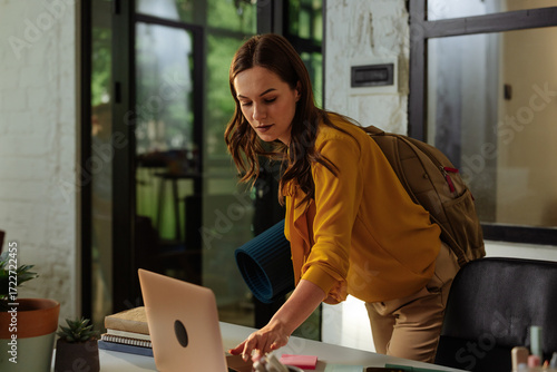 Businesswoman closing laptop before leaving office for yoga class