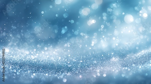 An abstract image featuring a gradient of blue hues, with a textured, glittering effect at the bottom, resembling snow or sparkles, and out-of-focus light orbs scattered throughout