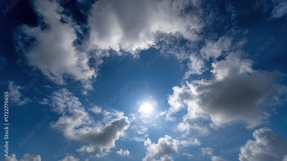 Obraz premium Azure sky is filled with puffy, brilliant white clouds surrounding the bright sun