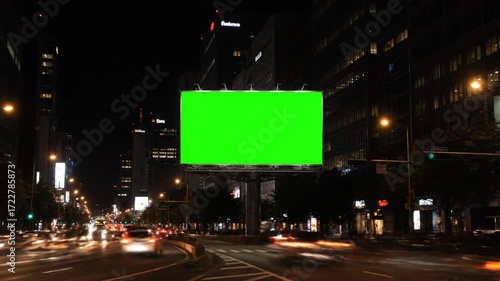 Billboard with green screen on a nighttime city traffic background. Mockup and copy space ready for VFX, motion graphics, advertising, and cinematic overlays.