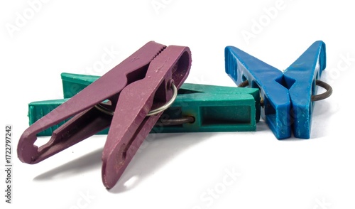 Three plastic clothespins. Brown, green and blue. Steel springs are visible. Isolated background.