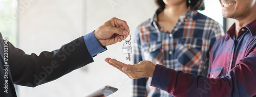 close up view hand of property realtor landlord giving key house to buyer tenant. banner wide side.