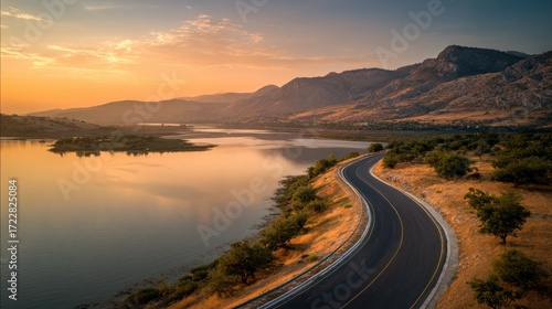 Serene Curving Road by Calm Lake at Sunset in Beautiful Landscape