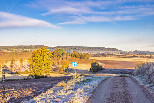 Rural landscape view at autumn with a gravel road and frost on the ground