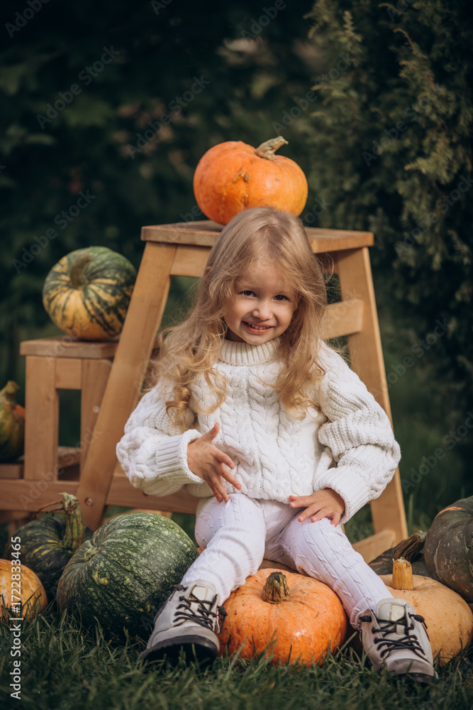 Fototapeta premium Little girl child in the garden with pumpkins