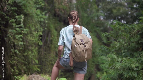 Female tourist with backpack is enjoying view of a forest