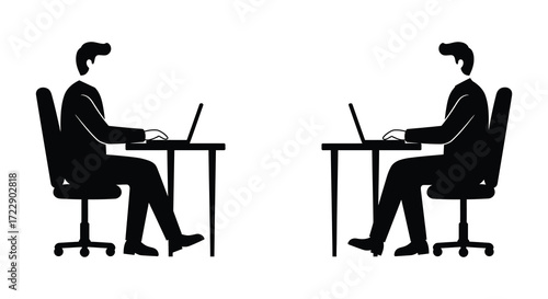 Two people working on laptops at desks facing each other