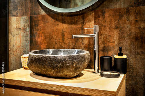 Luxury bathroom with stone sink, modern toilet, rustic wall tiles, and natural wood vanity. Contemporary spa-style interior with warm lighting and elegant design details.