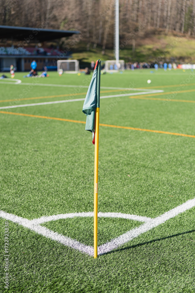 Fototapeta premium Soccer corner flag stands on a bright green field during a sunny day in a sports complex