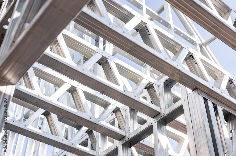 Obraz premium Structure of steel roof frame for building construction. Metal frame of the building with a sandwich panel of insulation on the wall. Construction of a new industrial building.