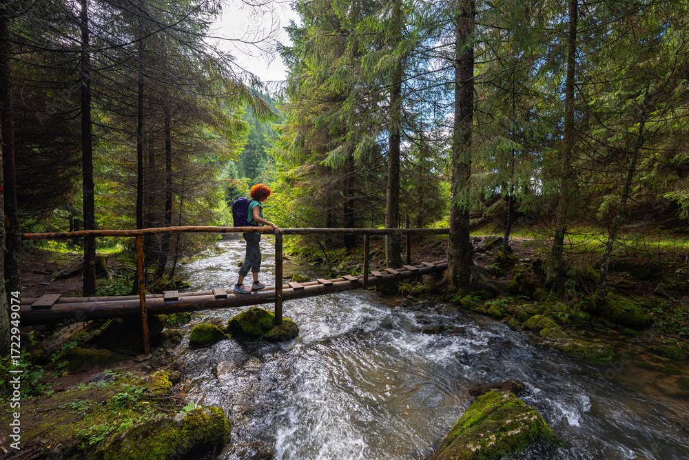 Obraz premium Active woman crossing bridge over Ponor creek