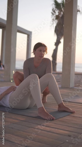 Pregnant woman doing yoga on the beach with a trainer. Girl Doing Glute Bridge