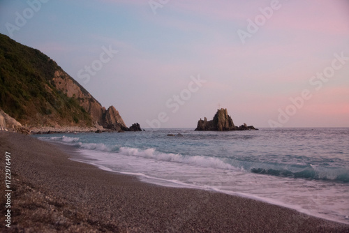 Sestri Ponente beach with scenic cross on rocky outcrop by the sea
