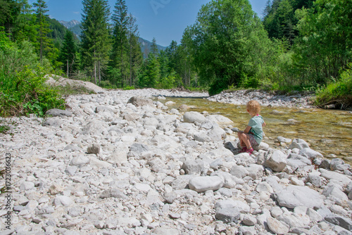 Child looking at scenic Slovenian river flowing through lush green valley