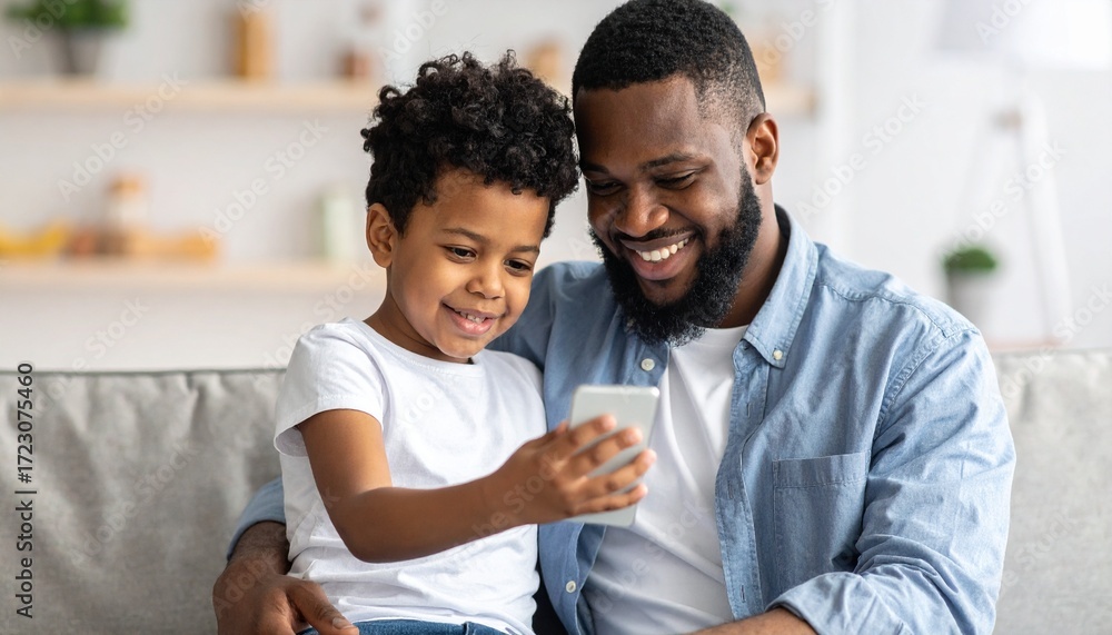 Fototapeta premium A young boy and his father looking at a mobile phone. Two generations learning technology together