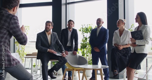 Business team meeting in modern office, speaker talking for startup strategy presentation to audience of employees. Group of managers listening speech of leader on corporate seminar or workshop
