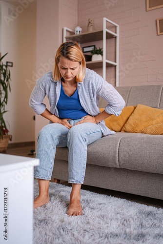 Wallpaper Mural Woman experiencing abdominal pain while sitting on sofa at home Torontodigital.ca