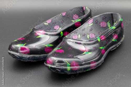 Photos Pair of colorful, patterned plastic clogs on a dark background, footwear concept