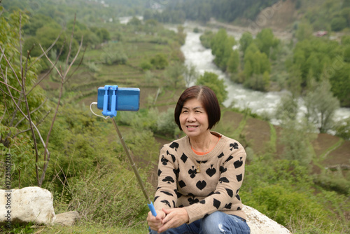 Canvas Print Asian female tourists take photos with her mobile phones at Pahalgam,It is a beautiful tourist city in the Kashmir region of India, nicknamed the Switzerland of India because of its natural beauty