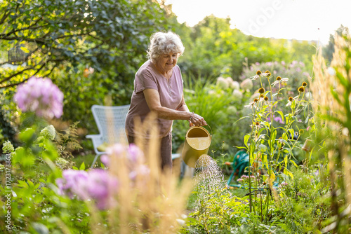 Senior woman watering plants in her garden

