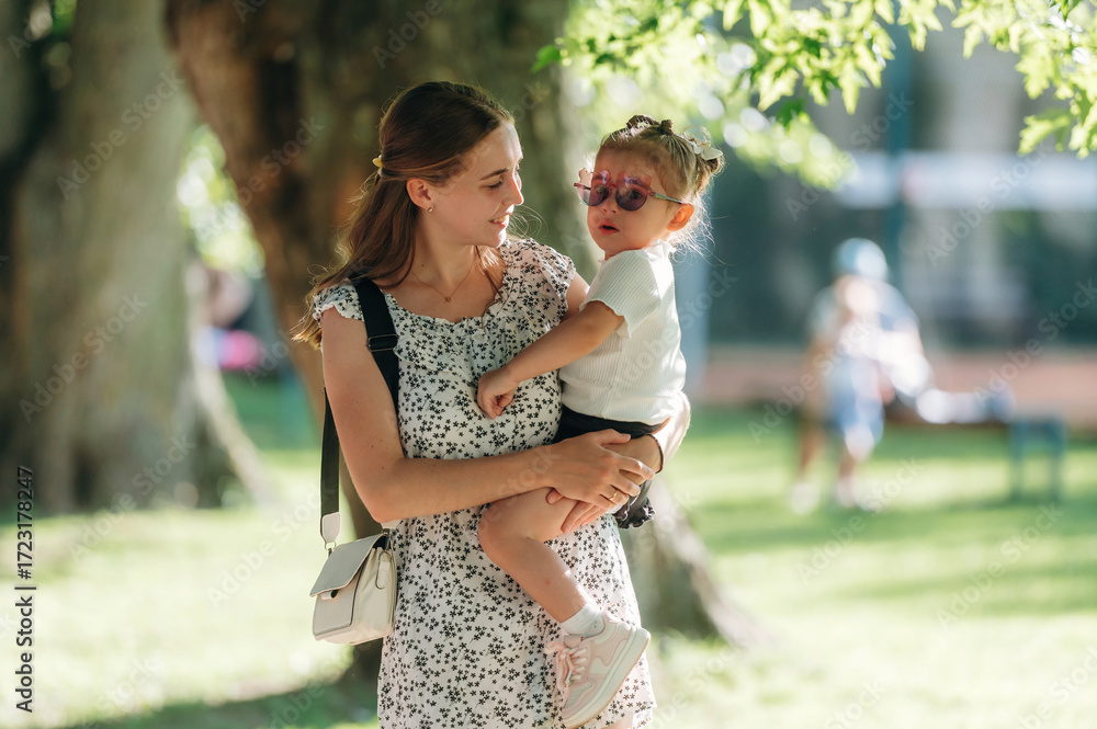 Obraz premium Mother is holding daughter in hands, having a walk in the park