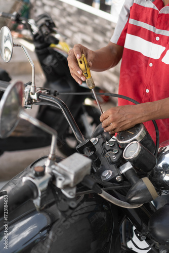 Mechanic man repairing motorcycle handlebar using screwdriver
