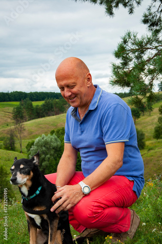 Man in nature with dog, showing love. Friendship and togetherness. Landscape portrait of man and pet dog outdoor. Pet companion for man. Travel with pet. Fresh air stroll