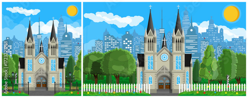 Catholic church building with green trees. Cityscape with houses and skyscraper building. Religious architecture.