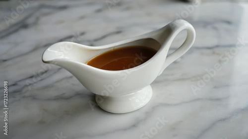 White porcelain creme brulee server with sauce in it. On a marble countertop.