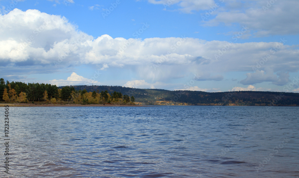 Obraz premium Bratskoye Reservoir with an autumn forest in the distance under a soft sky