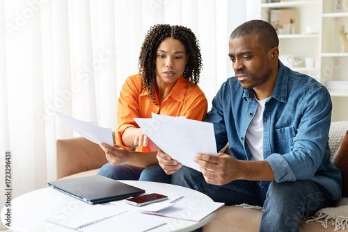 Fotografija Focused African American couple working on finances at home, reading documents and planning expenses