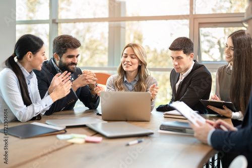 Satisfied business team looking at achieved project results on laptop in modern office