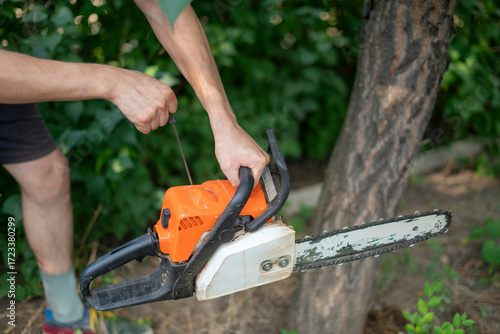 Wallpaper Mural Hands starting a chainsaw by jerking starter, ready to start cutting branches in a residential backyard Torontodigital.ca
