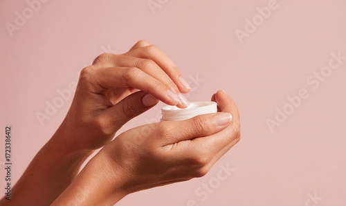 Close-up of Hands Applying Cream on Pastel Background