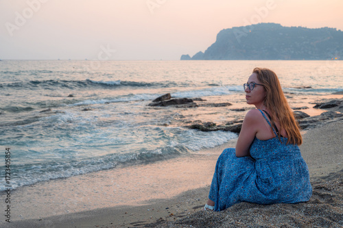 Woman sits on the beach and...