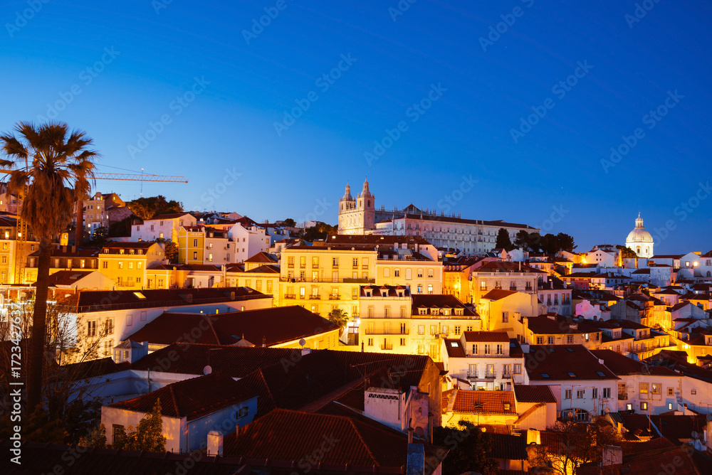 Obraz premium Panoramic Night View Over Alfama’s Rooftops and Tagus River from Miradouro da Graca Viewpoint in Lisbon, Portugal
