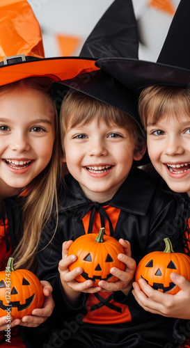 Smiling children in Halloween costumes hold carved pumpkins Close-up shot showcasing joy and festivity of the holiday